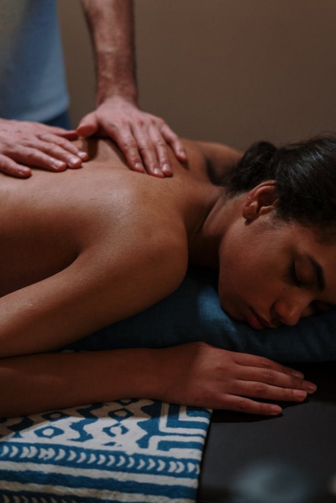 Relaxing massage therapy session with therapists hands on womans back in spa setting.
